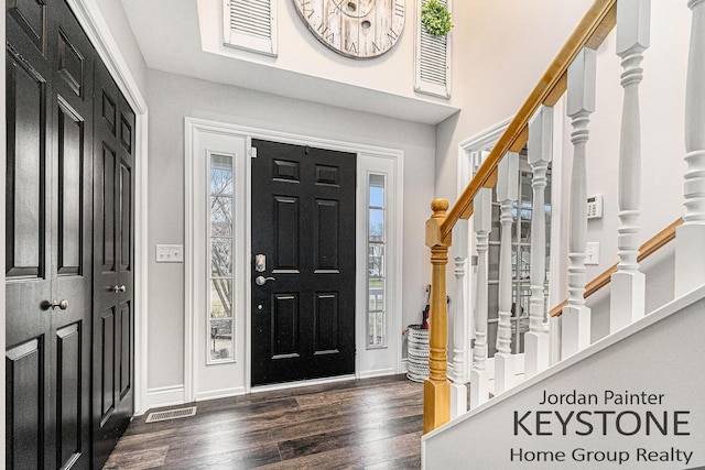 entryway with stairway, dark wood-style flooring, visible vents, and baseboards