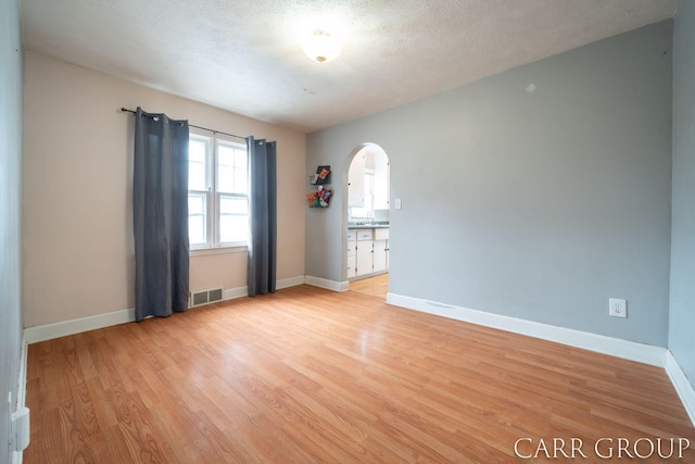 empty room featuring a textured ceiling and light wood-type flooring