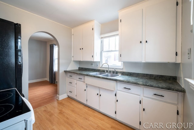 kitchen featuring sink, black fridge, white cabinetry, light hardwood / wood-style flooring, and electric range