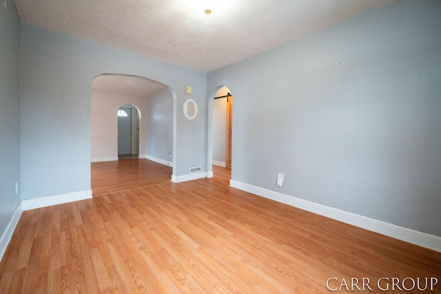 empty room with a textured ceiling and light hardwood / wood-style flooring