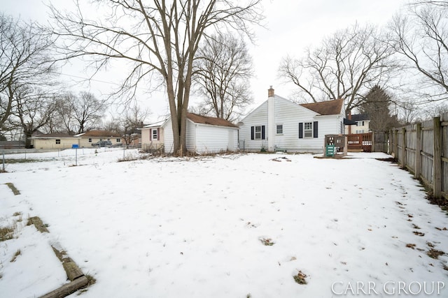 snow covered rear of property featuring a wooden deck and an outdoor structure