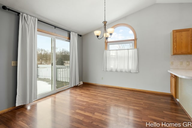 unfurnished dining area with lofted ceiling, a notable chandelier, and dark hardwood / wood-style floors