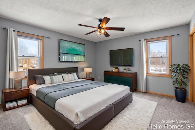 bedroom with multiple windows, light carpet, and a textured ceiling