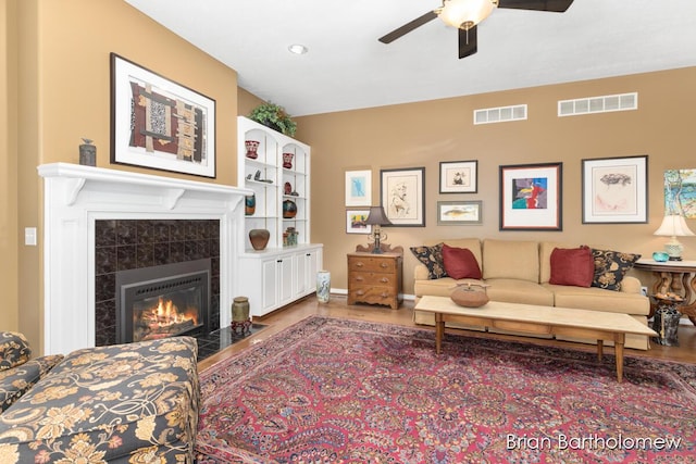 living room featuring hardwood / wood-style flooring, ceiling fan, and a fireplace