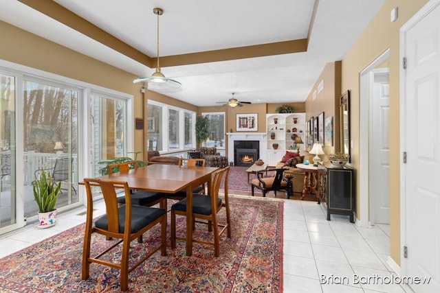 tiled dining room with built in features, a raised ceiling, and ceiling fan