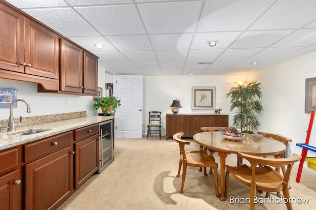 carpeted dining room with a drop ceiling, sink, and beverage cooler