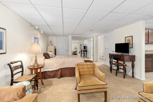 carpeted bedroom with ensuite bathroom and a paneled ceiling