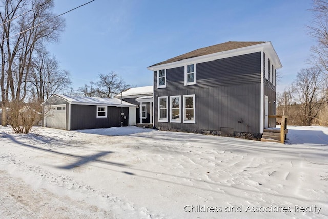 snow covered rear of property featuring an outbuilding