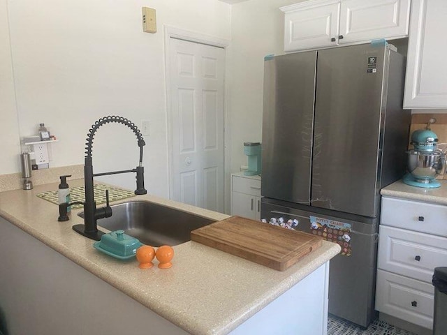 kitchen featuring light countertops, freestanding refrigerator, and white cabinets