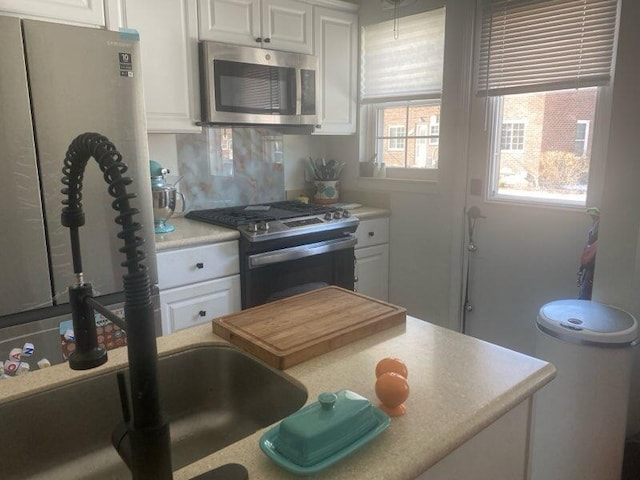 kitchen featuring appliances with stainless steel finishes, white cabinets, light countertops, and backsplash