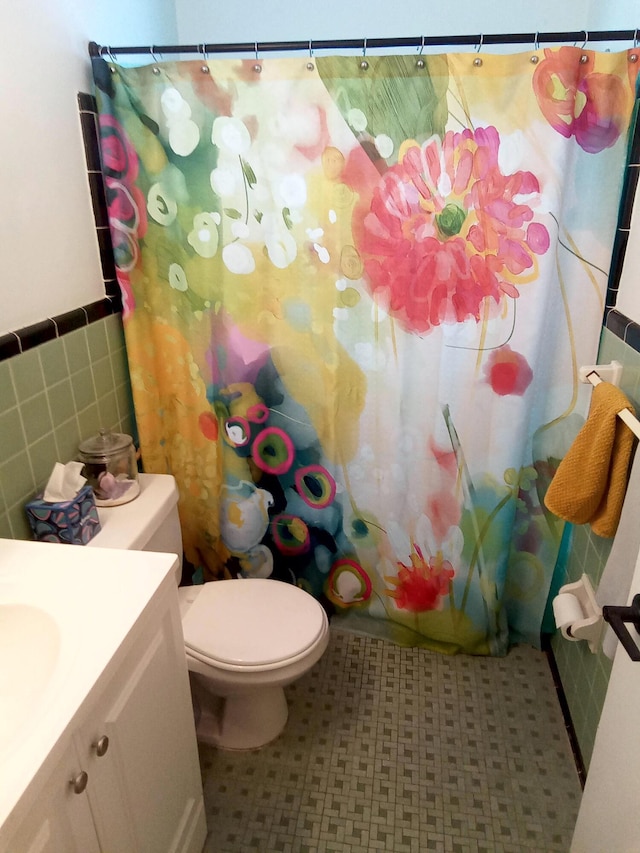 full bath with wainscoting, tile walls, toilet, and vanity