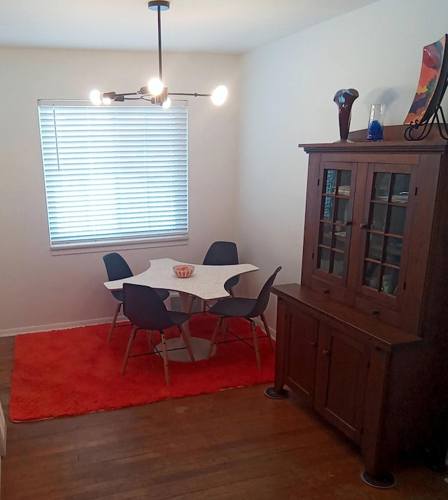 dining area featuring a chandelier, dark wood finished floors, and baseboards