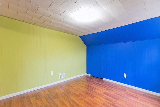 additional living space with hardwood / wood-style flooring and lofted ceiling