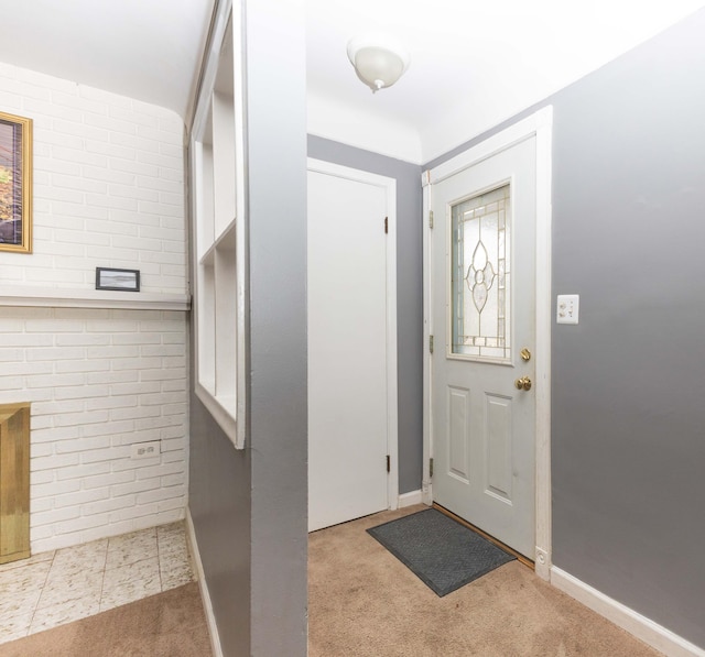 foyer with brick wall and light carpet