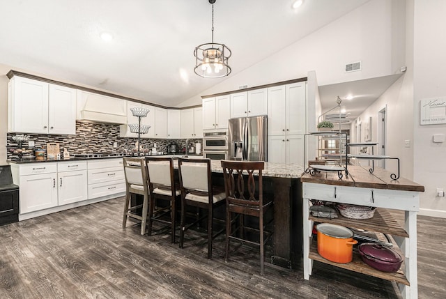 2678 Richmond St NW, Grand Rapids, MI 49504 - kitchen with decorative backsplash, a breakfast bar area, dark wood-style flooring, visible vents, and stainless steel fridge