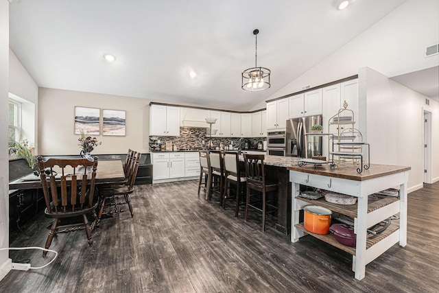 2678 Richmond St NW, Grand Rapids, MI 49504 - kitchen with dark wood-style flooring, stainless steel appliances, decorative light fixtures, backsplash, and vaulted ceiling