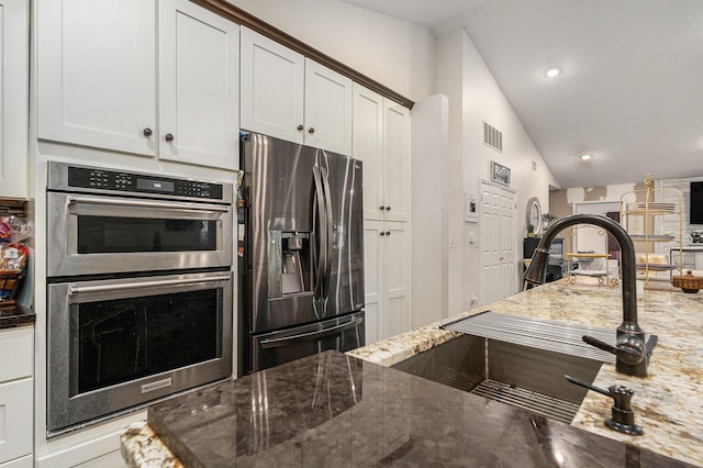 2678 Richmond St NW, Grand Rapids, MI 49504 - kitchen featuring visible vents, lofted ceiling, dark stone counters, a sink, and appliances with stainless steel finishes