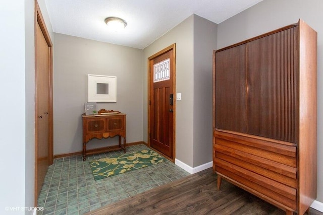 foyer with baseboards and dark wood-style flooring