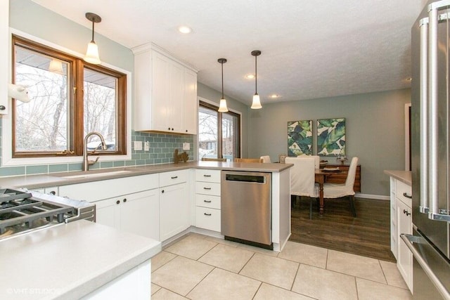 kitchen with appliances with stainless steel finishes, white cabinets, hanging light fixtures, and a peninsula