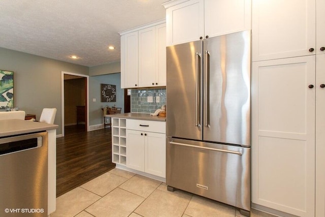 kitchen with light countertops, appliances with stainless steel finishes, decorative backsplash, and white cabinets