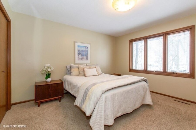 bedroom with baseboards, a closet, visible vents, and light colored carpet