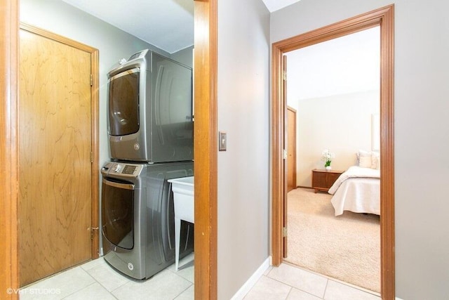 washroom featuring light carpet, laundry area, light tile patterned floors, and stacked washing maching and dryer