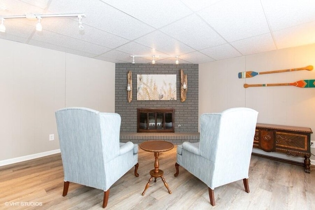 sitting room with a drop ceiling, a fireplace, track lighting, and wood finished floors