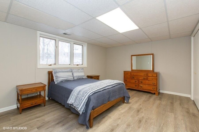 bedroom featuring light wood finished floors, a paneled ceiling, and visible vents