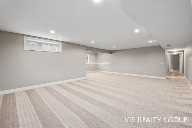 below grade area featuring baseboards, visible vents, recessed lighting, and light carpet