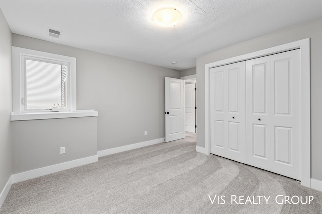 unfurnished bedroom featuring baseboards, visible vents, light colored carpet, and a closet