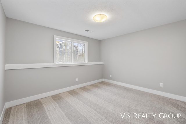 carpeted spare room featuring baseboards and visible vents