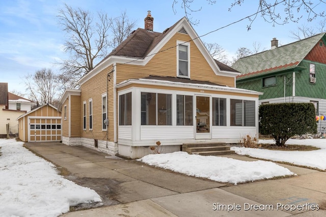 view of front of property with an outbuilding, a garage, and a sunroom