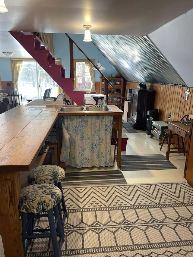 office space featuring a healthy amount of sunlight, wood walls, vaulted ceiling, and a sink