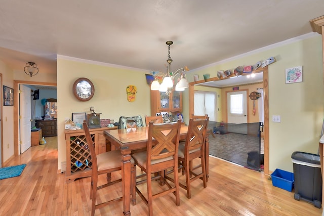 dining room with ornamental molding, a chandelier, and light hardwood / wood-style floors