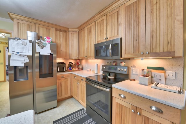 kitchen with light stone counters, stainless steel appliances, and light brown cabinetry