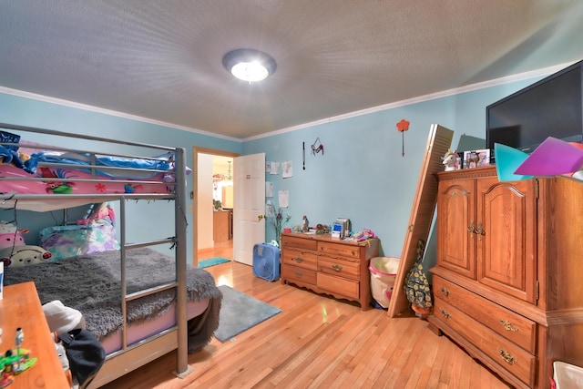 bedroom featuring ornamental molding, light hardwood / wood-style floors, and a textured ceiling