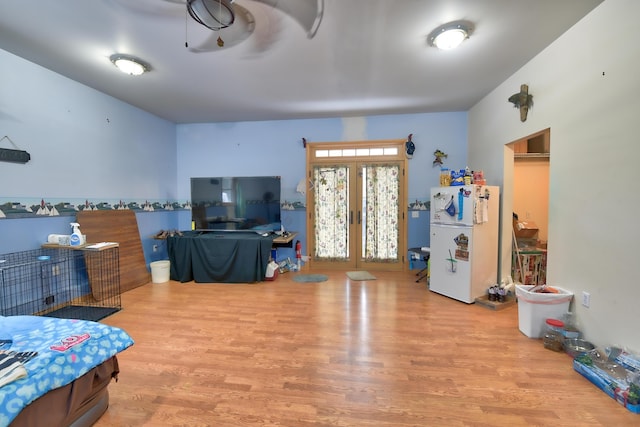 bedroom featuring white refrigerator, light wood-type flooring, and french doors