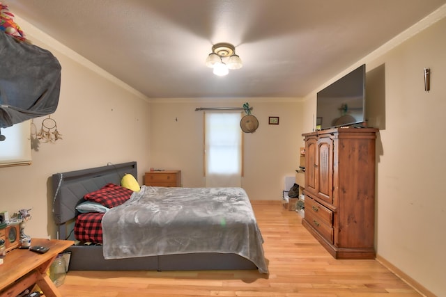 bedroom featuring ornamental molding and light hardwood / wood-style flooring