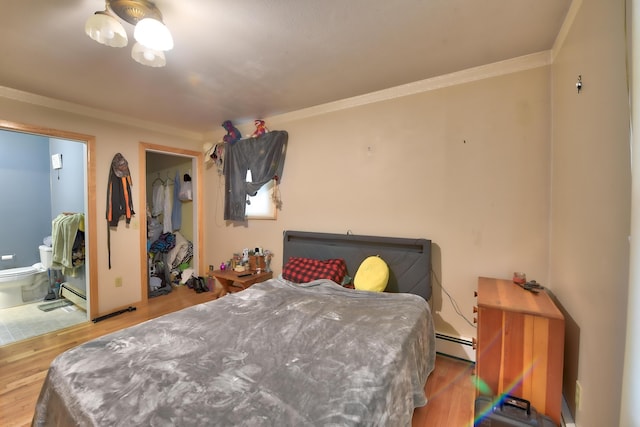 bedroom featuring hardwood / wood-style flooring, crown molding, a baseboard heating unit, and ensuite bath