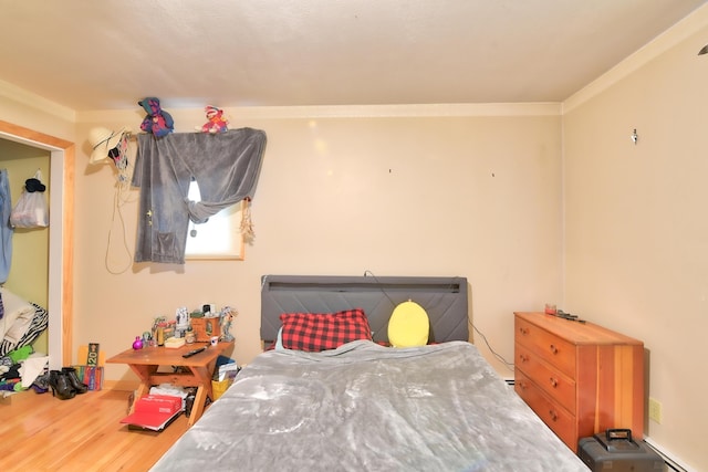 bedroom with hardwood / wood-style flooring, ornamental molding, and a baseboard radiator