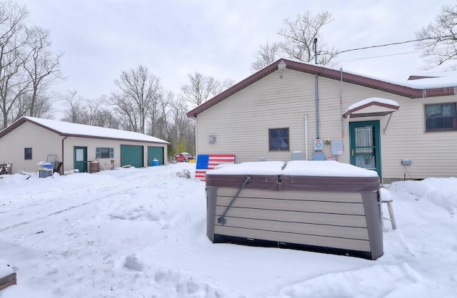 snow covered property featuring a hot tub and an outbuilding