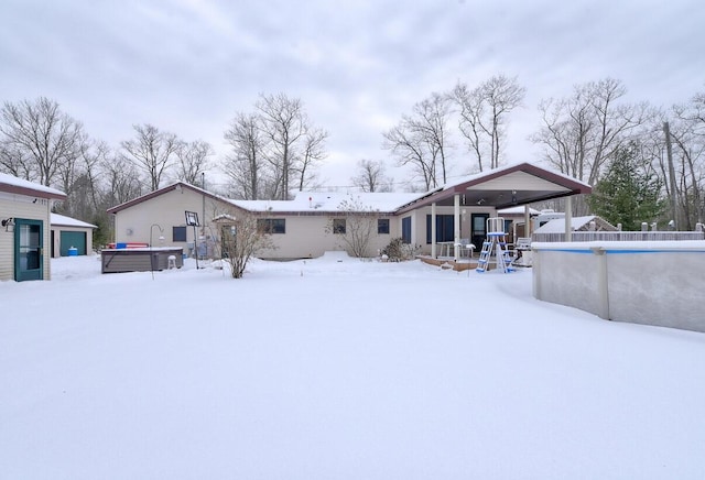 snow covered property featuring a swimming pool with hot tub