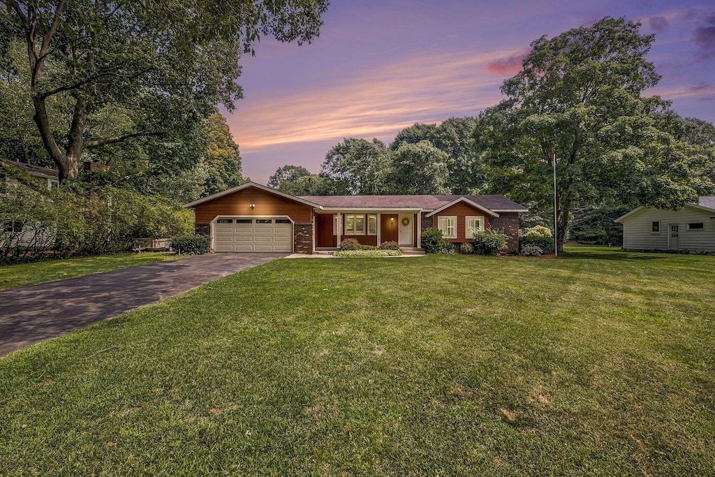 ranch-style house with a garage and a lawn