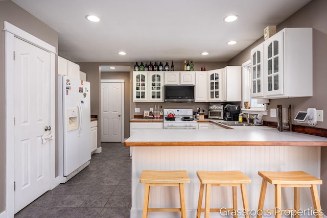 kitchen with sink, a breakfast bar area, white cabinets, kitchen peninsula, and white appliances