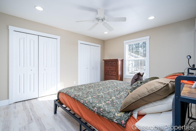 bedroom featuring ceiling fan, light hardwood / wood-style flooring, and multiple closets