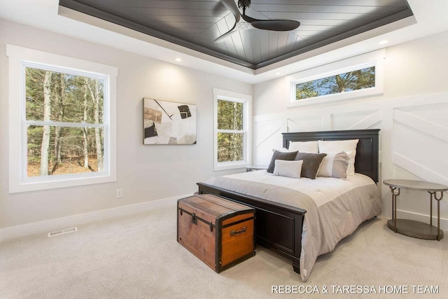 bedroom featuring light carpet, wood ceiling, and a raised ceiling