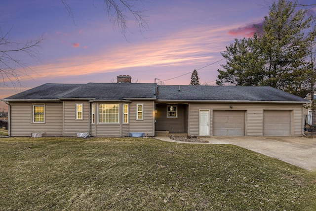 single story home featuring a garage and a lawn