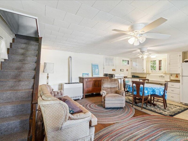 living room with heating unit, hardwood / wood-style floors, and ceiling fan