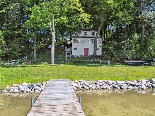 view of dock with a yard and a water view