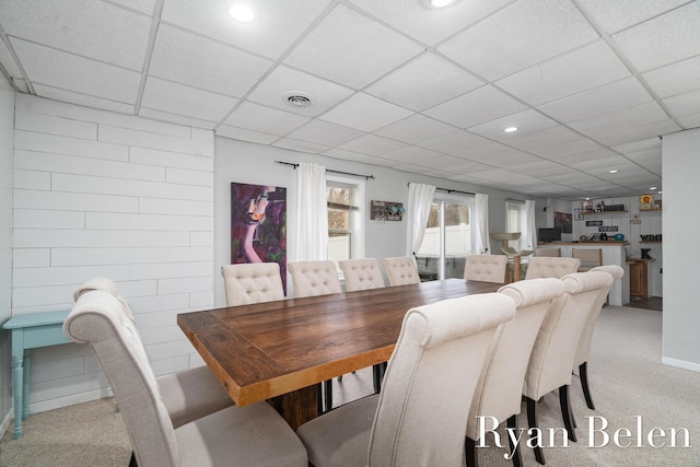 dining area with light carpet and a paneled ceiling